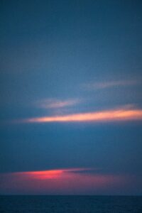 Stunning sunset skies over the sea, with shades of deep blue and vibrant pink, viewed from the 'CALIU' during a serene sunset tour.