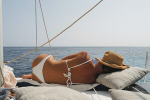 Relaxed sunbathing on the serene deck of 'CALIU', with the tranquil sea extending to the horizon, exemplifying the peaceful sailing experience on Formentera's waters.