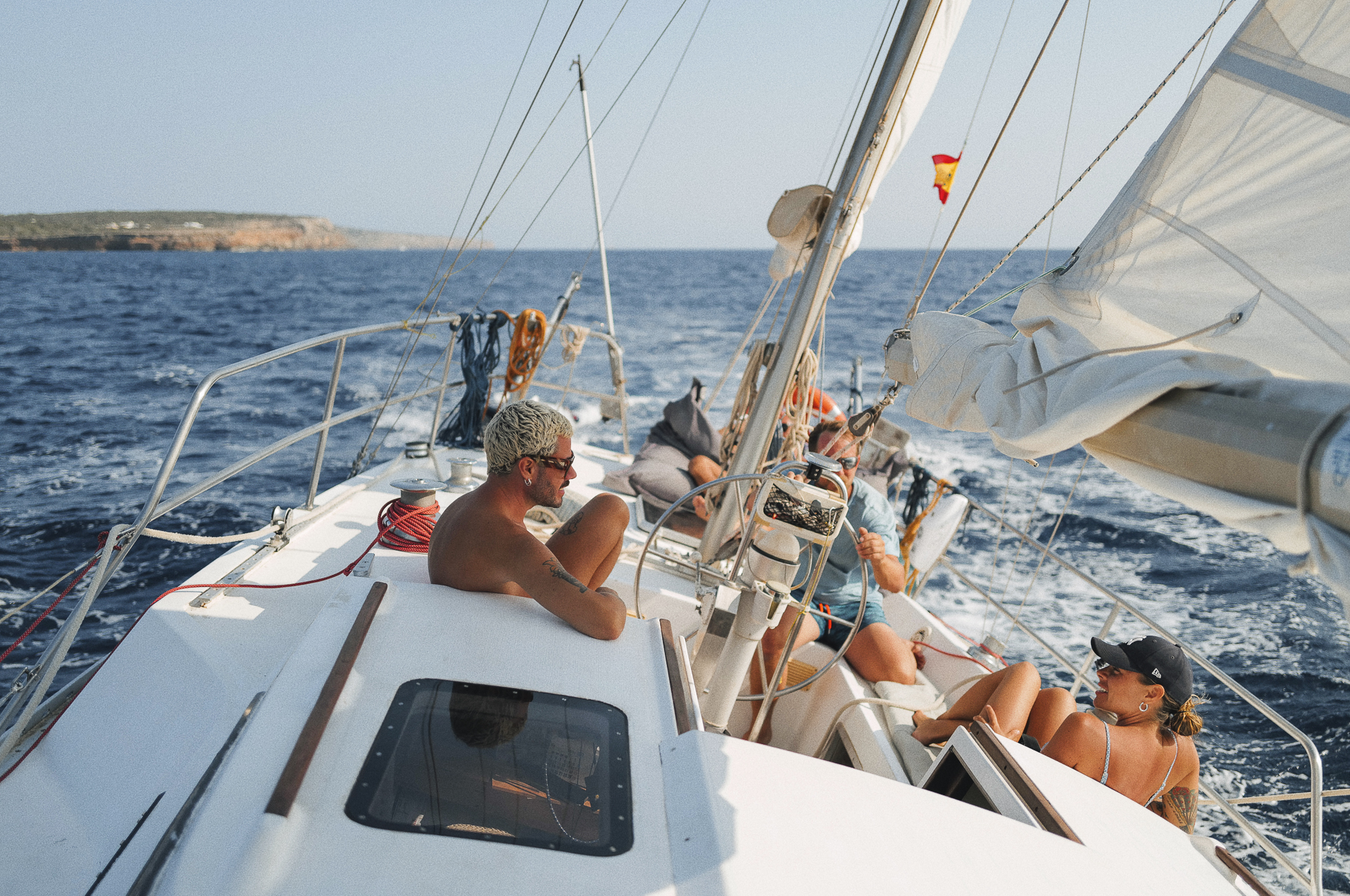 Guests relish a full-day sailing adventure on the 'CALIU', feeling the thrill of the wind as the sails billow on a breezy day, ensuring a journey that is both safe and comfortable off Formentera's coast.