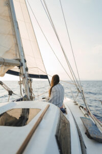 Passenger enjoying the tranquil seascape on a half-day sail around Formentera aboard the 'CALIU', with sails billowing in the gentle breeze.