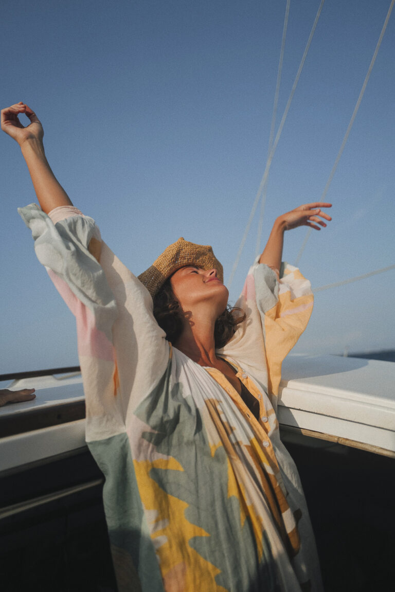 Woman with arms raised, basking in the freedom and joy of a full-day sailing tour on the 'CALIU' around Formentera's serene seas.